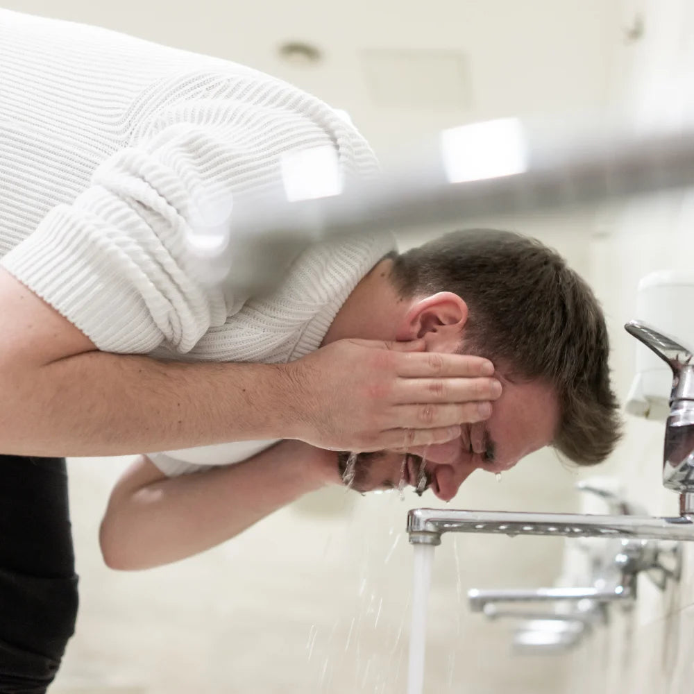 a man performing wudhu from water coming out of a tap