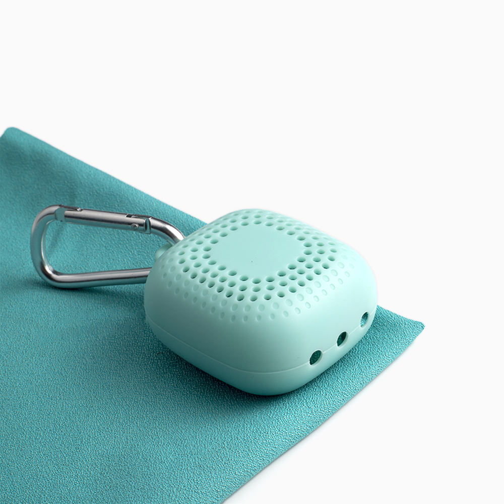 A portable wudhu towel in light blue color, laid out flat with a compact green case with a carabiner clip on top