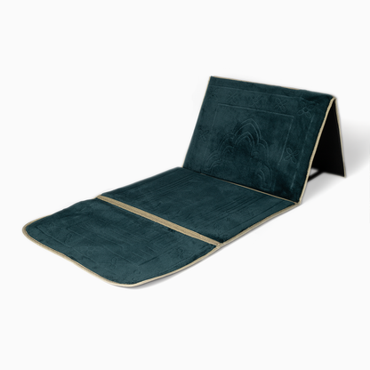 A dark emerald green folded padded prayer rug with a geometric pattern, featuring a backrest.