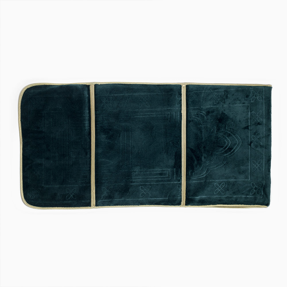 full view of dark emerald green prayer rug lying on the ground.
