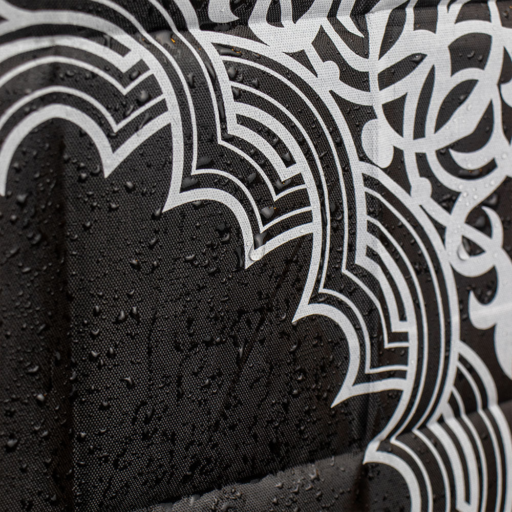 A black portable prayer mat shown with water droplets on its surface
