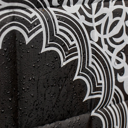 A black portable prayer mat shown with water droplets on its surface